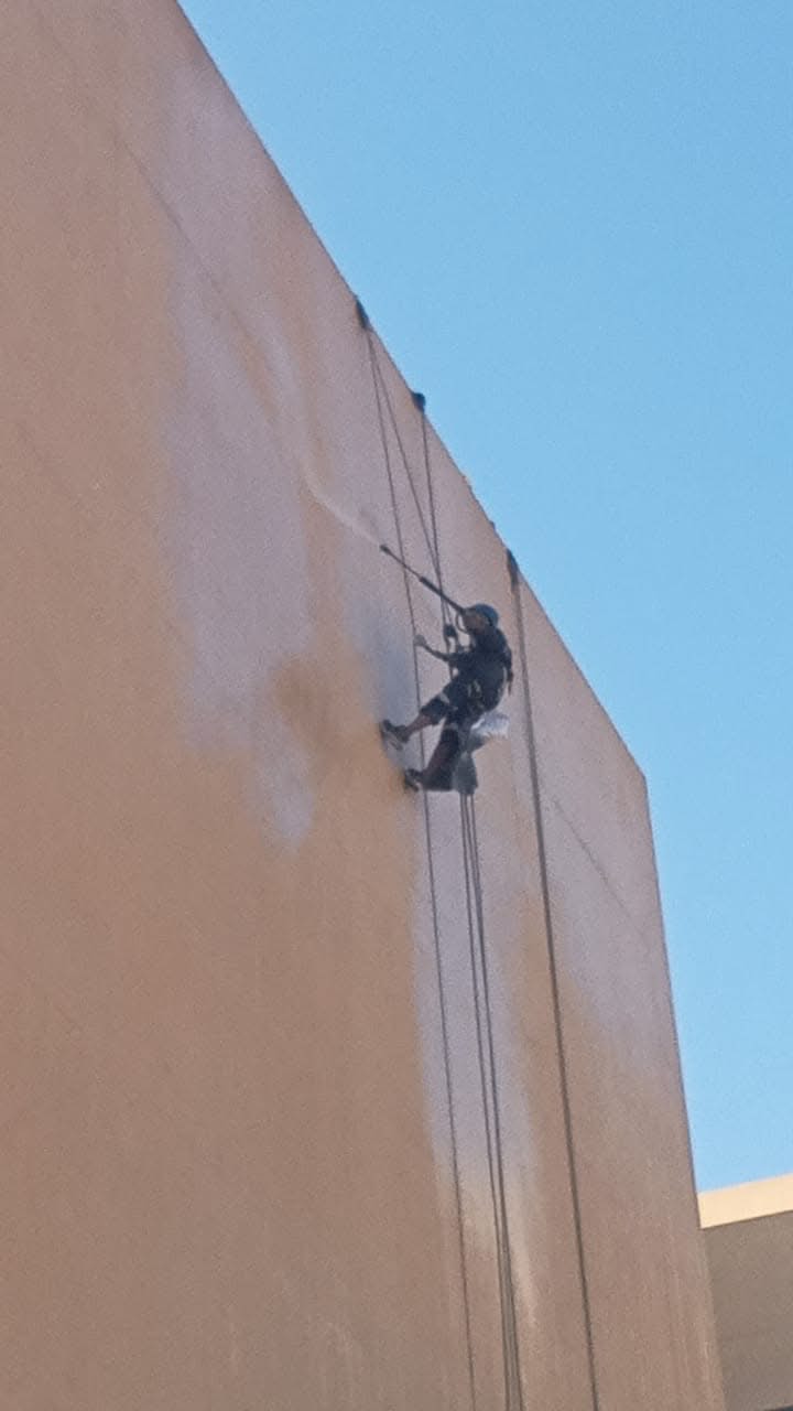 Rope-access painter applying exterior wall coating